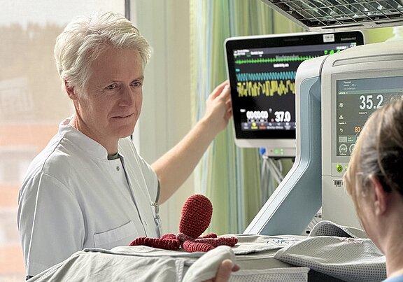 Dr. Hillebrand an einem Frühchenbett mit Monitor