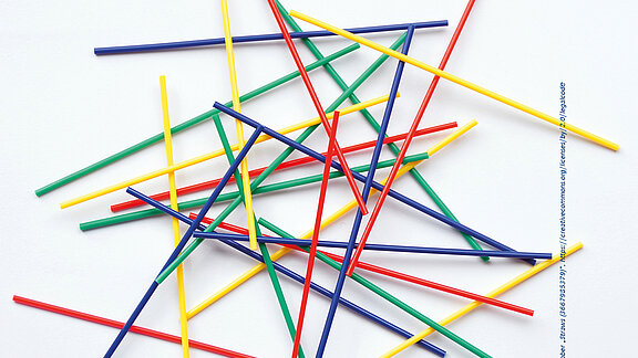 Dünne Stäbe in rot, grün, gelb und blau liegen kreuz und quer übereinander.