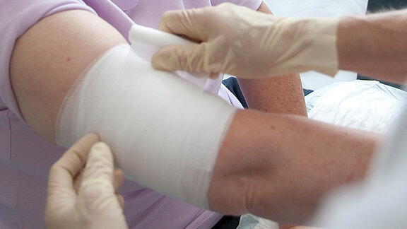 Ein Verband wird am Arm einer Patientin angelegt.