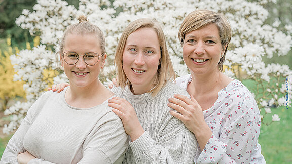 3 Mitarbeiterinnen vom Team der Hebammenpraxis Elmshorn vor einerm Magnolienstrauch.