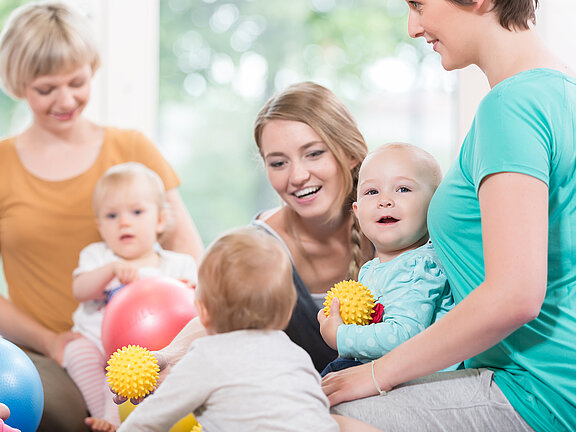 Mütter und Babys beim Turnen mit Bällen.