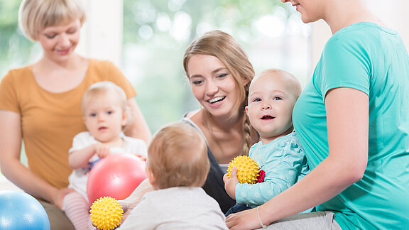 Mütter und Babys beim Turnen mit Bällen.