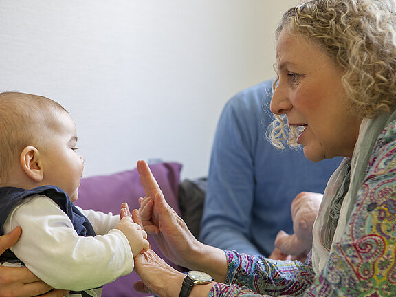 Therapeutin Heike Brosch mit einem Baby und deren Eltern in der Therapiesituation.