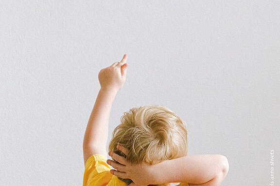 Ein Junge im gelben T-Shirt zeigt nach oben.