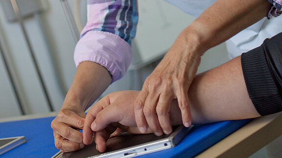 Eine Hand wird zum Röntgen vorbereitet.