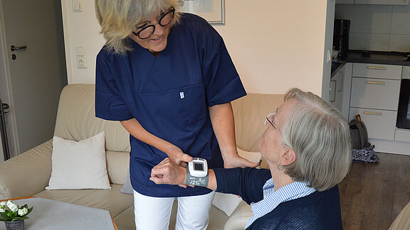 Die Mitarbeiterin des Ambulanten Pflegedienstes misst den Puls der Kundin