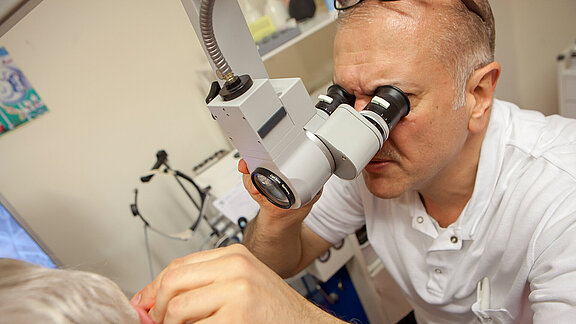 Hals-Nasen-Ohrenarzt Dr. Ayham Said untersucht den Gehörgang einer Patientin.