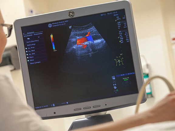 Medizinische Fachkraft hält das Sonografiegerät auf den Bauch der Patientin.
