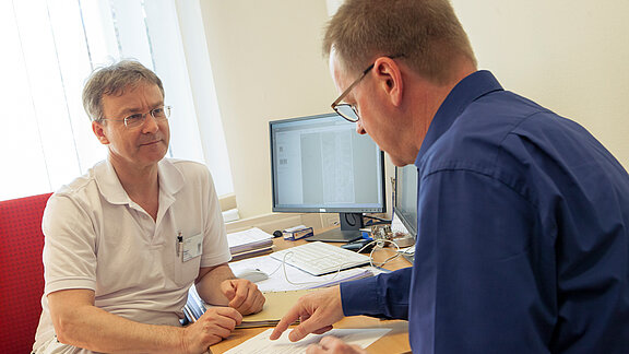Dr. med. Wolfram Kluge in der Sprechstunde im Gespräch mit einem Patienten.