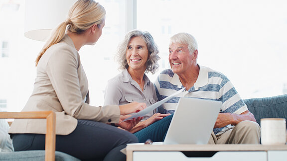 Ein älteres Paar wird von einer Mitarbeitern beraten.