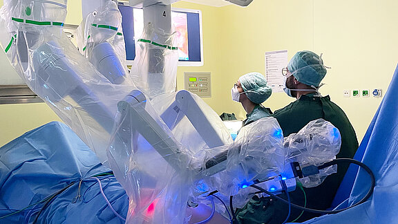 Eine weibliche und eine männliche Person vom medizinischen Fachpersonal arbeiten am OP-Roboter Da Vinci.