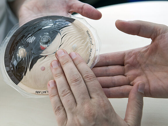 Hände tasten ein Brustmodell ab.