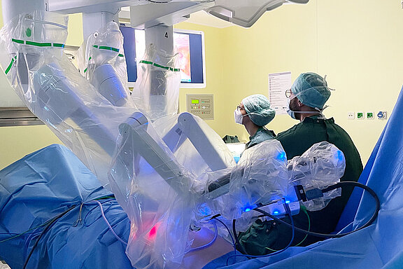 Eine weibliche und eine männliche Person vom medizinischen Fachpersonal arbeiten am OP-Roboter Da Vinci.