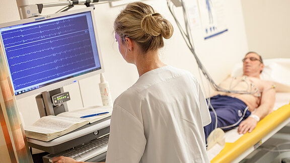 Patient liegt auf Untersuchungsliege und eine Mediziner schaut auf dem Monitor.