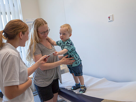 Kinderärztin unterhält sich mit einer Mutter und Ihrem Kind im Untersuchungszimmer.
