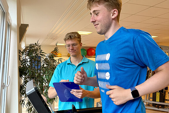 Trainierende Person auf Laufband wird von einem MediFit-Mitarbeitenden betreut.