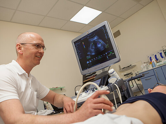 Leitender Arzt der Gefäßchirurgie Dr. med. Jörn Pfeiffenberger untersucht eine Patientin per Sonografie.