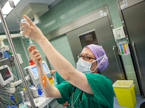 OP-Fachkraft im Operationssaal kontrolliert die Infusion.